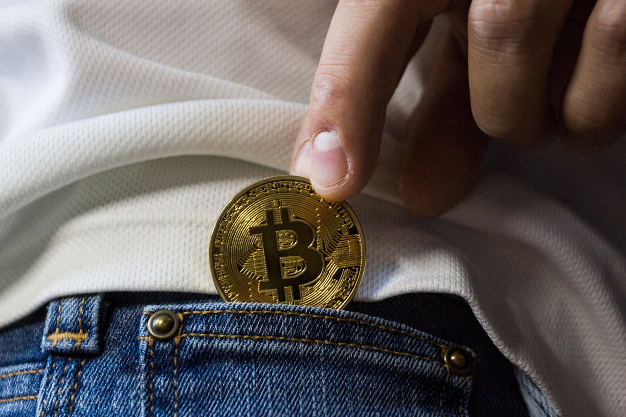 services-01 Close-up of hand putting Bitcoin in jeans pocket symbolizing cryptocurrency savings.